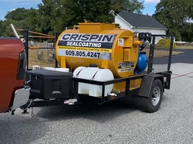 A yellow sealcoating tank on a black trailer